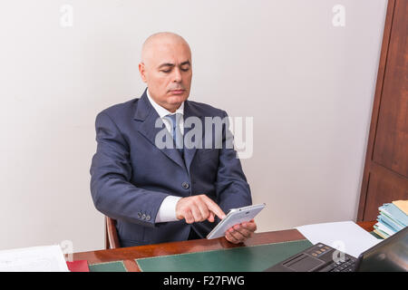 Der Mann am Schreibtisch, betrachten Sie Ihre i Pad/Tablet, in seinem Büro. Stockfoto