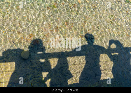 Schatten der Mitglieder einer Familie spiegelt sich in einem Fluss beim Ansehen von einer Brücke Stockfoto