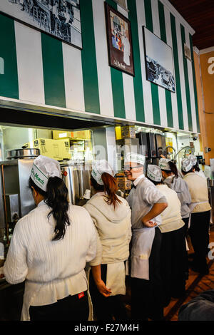 Das Personal an der Café du Monde Line-up zu ihrer Lieferung von Krapfen und Kaffee im French Quarter, New Orleans LA bereit Stockfoto