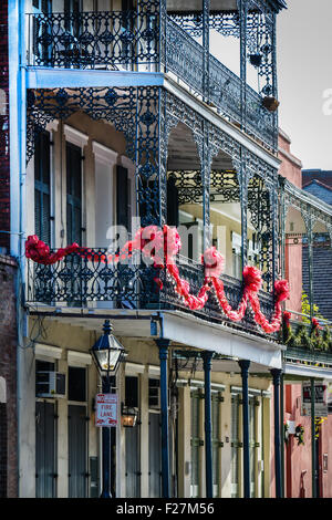 Eine Creole Stadthaus mit reich verzierten schwarzen schmiedeeisernen Balkonen verziert mit roten Girlande für den Urlaub in New Orleans, LA Stockfoto