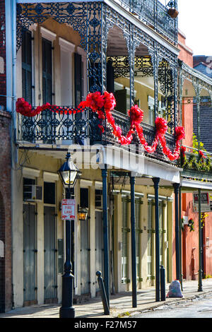 Eine Creole Stadthaus mit reich verzierten schwarzen schmiedeeisernen Balkonen verziert mit roten Girlande für den Urlaub in New Orleans, LA Stockfoto