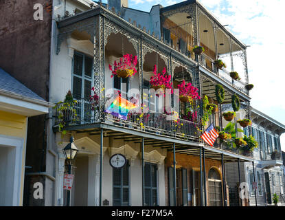 Eine Creole Stadthaus mit reich verzierten schmiedeeisernen Balkonen, hängenden Blüten und Regenbogenfahne im French Quarter von New Orleans, LA Stockfoto