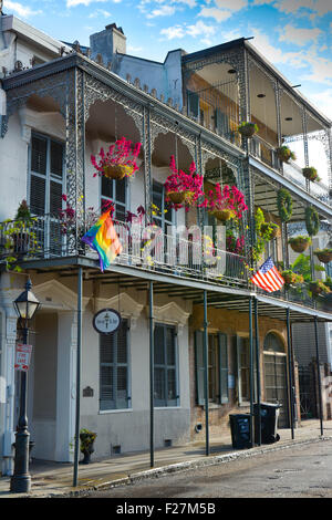 Eine Creole Stadthaus mit reich verzierten schmiedeeisernen Balkonen, hängenden Blüten und Regenbogenfahne im French Quarter von New Orleans, LA Stockfoto