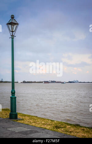 Eine zentrierte einzigen antiken Stil Laternenpfahl mit Blick auf das Flussufer auf dem mächtigen Mississippi in New Orleans, LA Stockfoto