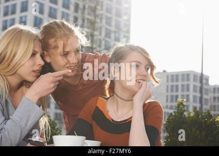 Teenage Girl zeigt etwas an ihre Freunde in einem Straßencafé, München, Bayern, Deutschland Stockfoto