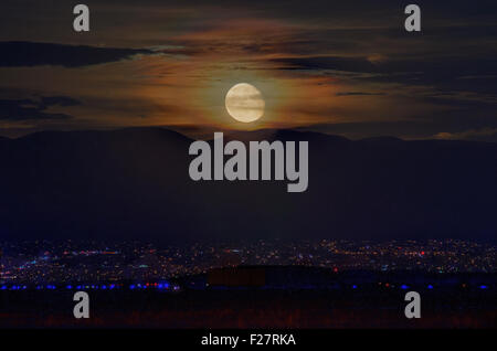 Fast Vollmond Aufstieg über Albuquerque und die Sandia Mountains, New Mexico, USA. Stockfoto