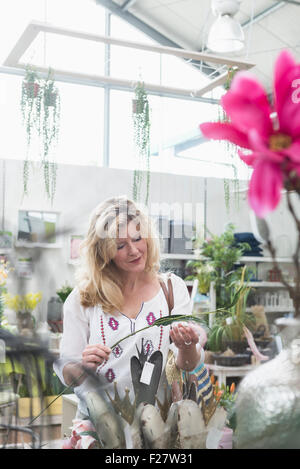 Reife Frau shopping für künstliche Blume im Garten-Center, Augsburg, Bayern, Deutschland Stockfoto