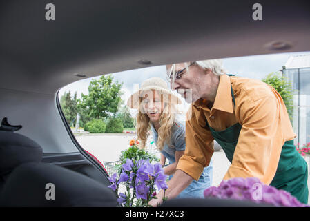 Shop Assistant hilft einen Kunden setzen Anlage im Kofferraum, Augsburg, Bayern, Deutschland Stockfoto