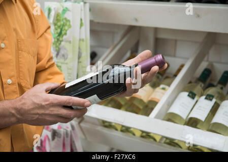 Kunden lesen Etikett auf einer Weinflasche im Supermarkt, Augsburg, Bayern, Deutschland Stockfoto