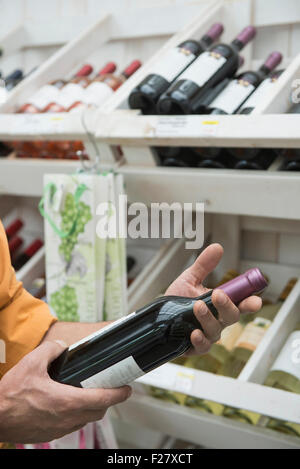 Kunden lesen Etikett auf einer Weinflasche im Supermarkt, Augsburg, Bayern, Deutschland Stockfoto