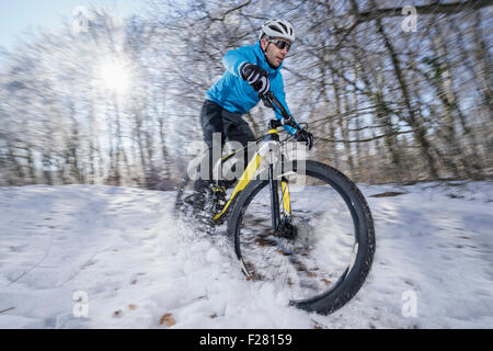 Mountainbiker, die mit dem Fahrrad in einem verschneiten Wald, Bayern, Deutschland Stockfoto