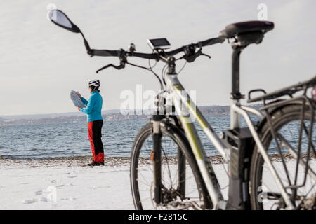 Seitenansicht der Reife Frau lesen Karte am Strand, Bayern, Deutschland Stockfoto