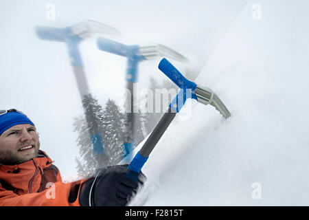 Männliche Bergsteiger hinauf verschneiten Hang mit Axt, Zell Am See, Österreich Stockfoto