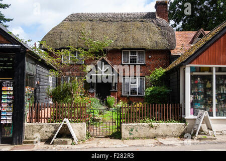 England, New Forest, Burley. Bezauberndes malerisches Strohdach zweistöckiges Landhaus zurück von der Straße zwischen zwei anderen Häuser. Stockfoto