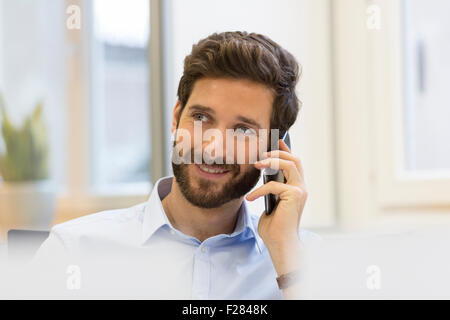 bärtige Geschäftsmann reden über Handy im Büro Stockfoto