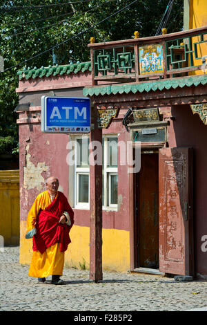 Mönch, vorbei an einem Gebäude für Geldautomaten in das buddhistische Gandan Kloster, Ulaanbaatar, Mongolei Stockfoto