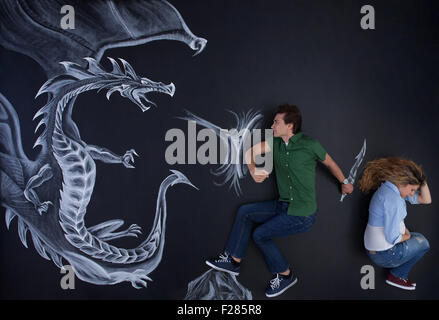 Junger Mann seine schwangere Frau gegen einen furchtlosen Zeichnung Drachen zu schützen. Stockfoto