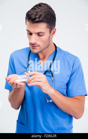 Porträt eines schönen männlichen Arztes stehend mit Tabletten isoliert auf weißem Hintergrund Stockfoto