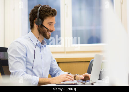 bärtiger Mann tragen Kopfhörer mit laptop Stockfoto