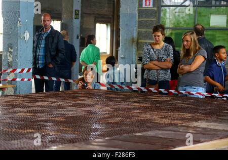 Brüssel, Belgien. 13. Sep, 2015. Besucher sehen eine riesige Schokolade in einer Schokoladenfabrik in Tongeren, Belgien, 13. September 2015. Die Fabrik produzierte Schokolade, 21 Meter lang, 5 Meter in der Breite und 1000 kg Gewicht und legte es auf Anzeige am Sonntag, im Rahmen des belgischen Heritage Days. Bildnachweis: Gong Bing/Xinhua/Alamy Live-Nachrichten Stockfoto