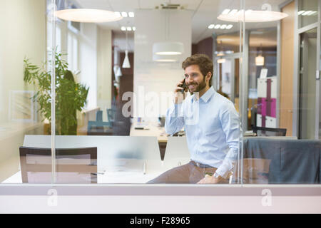 Eine lässige Geschäftsmann auf dem Handy im open Space office Stockfoto