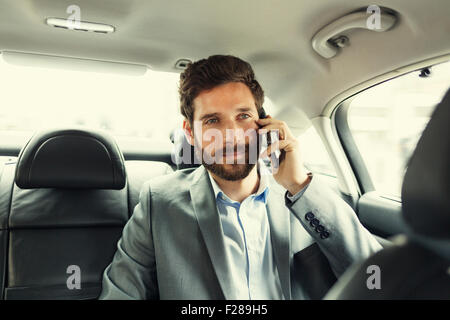 Lässige Geschäftsmann auf Handy im Heck des Autos Stockfoto