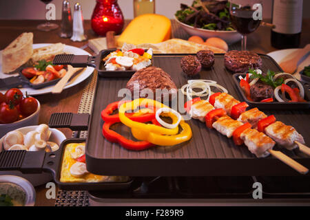 Schweizer Raclette oder die niederländische Variante "Gourmetten". Eine Tabelle mit Zutaten für ein Gericht, die in der Regel auf Celebrato serviert wird gefüllt Stockfoto