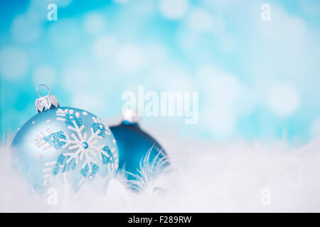 Blau und Silber Weihnachtskugeln auf eine weiche federleichte Oberfläche vor defokussierten blaue und weiße Lichter. Stockfoto