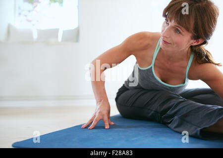 Bild der Frau Biegung nach vorn beim Yoga. Fitness-Frau praktizieren Yoga auf Trainingsmatte am Gym wegsehen. Stockfoto