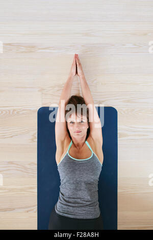 Draufsicht der Frau liegt am Boden, die stretching-Übung zu tun. Fitness-Frau Ausübung auf Yoga-Matte. Stockfoto
