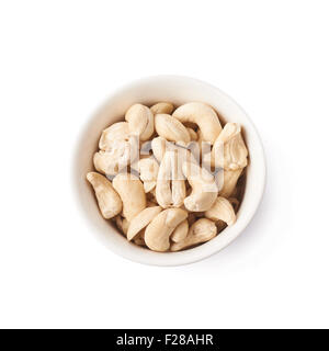 Schüssel gefüllt mit mehreren Cashewnüssen isoliert auf weißem Hintergrund, Draufsicht über Zusammensetzung Stockfoto