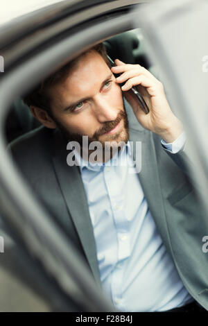 Lässige Geschäftsmann auf Handy im Heck des Autos Stockfoto