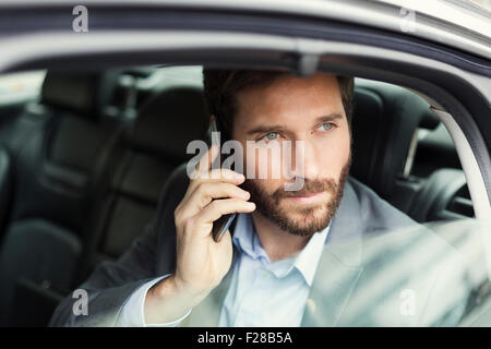 Lässige Geschäftsmann auf Handy im Heck des Autos Stockfoto