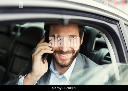 Fröhliche Geschäftsmann auf Handy im Heck des Autos Stockfoto