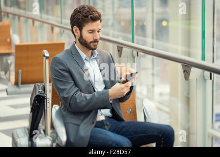 Mann in der Halle-Flughafen. SMS auf Handy tippen Stockfoto