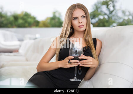 Porträt von attraktiven Frau im schwarzen Kleid mit Rotwein im Restaurant sitzen Stockfoto