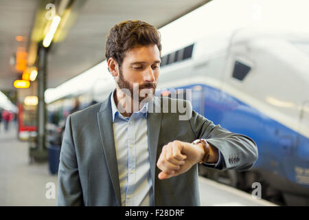 Mann sieht seine Uhr auf der Plattform-station Stockfoto