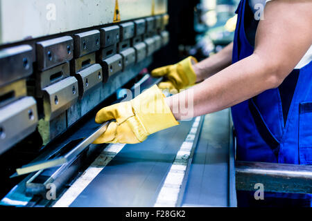 Asiatische Arbeiter in der Fabrik am Metall überspringen Maschine setzen Werkstück in Stockfoto