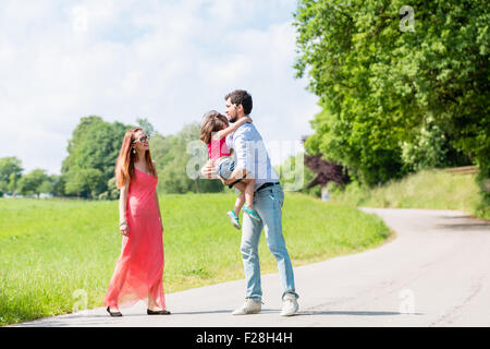 Mama, Papa und Tochter, die zu Fuß unterwegs im Sommer Stockfoto