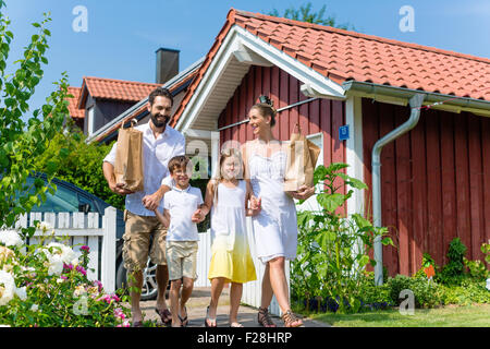 Familie war einkaufen, jetzt tragen Lebensmittel vom Auto zum Haus in Papiertüten Stockfoto