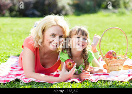 Happy Family im Urlaub Konzept. Mutter und Tochter Mädchen mit Picknick im Park im Freien spielen. Stockfoto