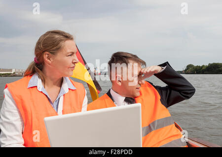 Geschäftsleute, die auf einem Boot sitzen und an einem Laptop arbeiten, Hamburg, Deutschland Stockfoto