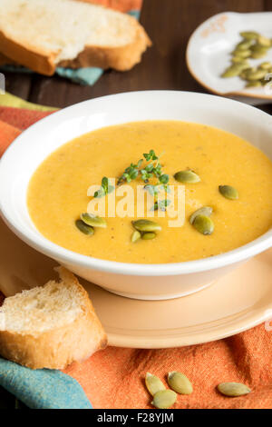 Kürbis Cremesuppe mit Kürbiskernen und Kräutern in Schüssel auf rustikalen Holztisch Stockfoto