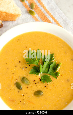 Kürbis Cremesuppe mit Kürbiskernen, Gewürze und Petersilie in Schüssel auf rustikale weißen Tisch Stockfoto