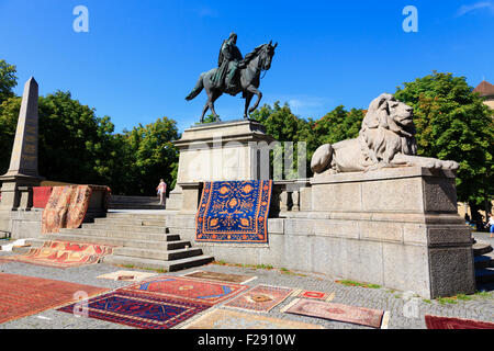 Denkmal für Kaiser Wilhelm 1, Karlsplatz, Stuttgart, Deutschland. Der Markttag mit Teppichen für Verkauf Draper über die Statue-Basis. Stockfoto