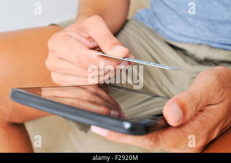 Closeup von einem kaukasischen Jüngling Online-shopping mit Kreditkarte über Tablet-computer Stockfoto