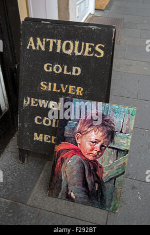 Kitschige Gemälde eines kleinen jungen Weinen neben einer pro Board Schild ein Antiquitätengeschäft in der Cockburn Street in Edinburghs Altstadt. Stockfoto