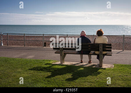 Paar sitzen auf einer Bank am Meer Blick Meer in Bexhill-on-Sea, East Sussex, England, Großbritannien Stockfoto