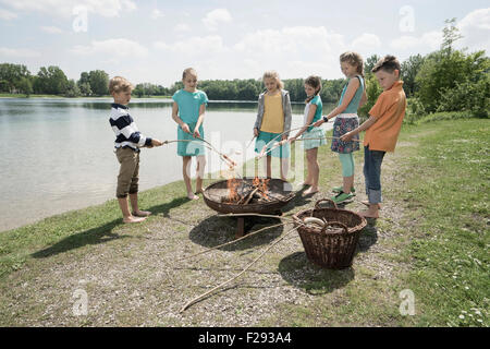 Gruppe von Freunden vorbereiten Würstchen am Lagerfeuer, Bayern, Deutschland Stockfoto