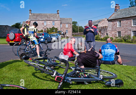 Begeisterte Radfahrer sammeln bei Sonnenschein auf Greystoke Dorfplatz, Cumbria, um die Ankunft der Tour of Britain 2015 Race erwarten Stockfoto